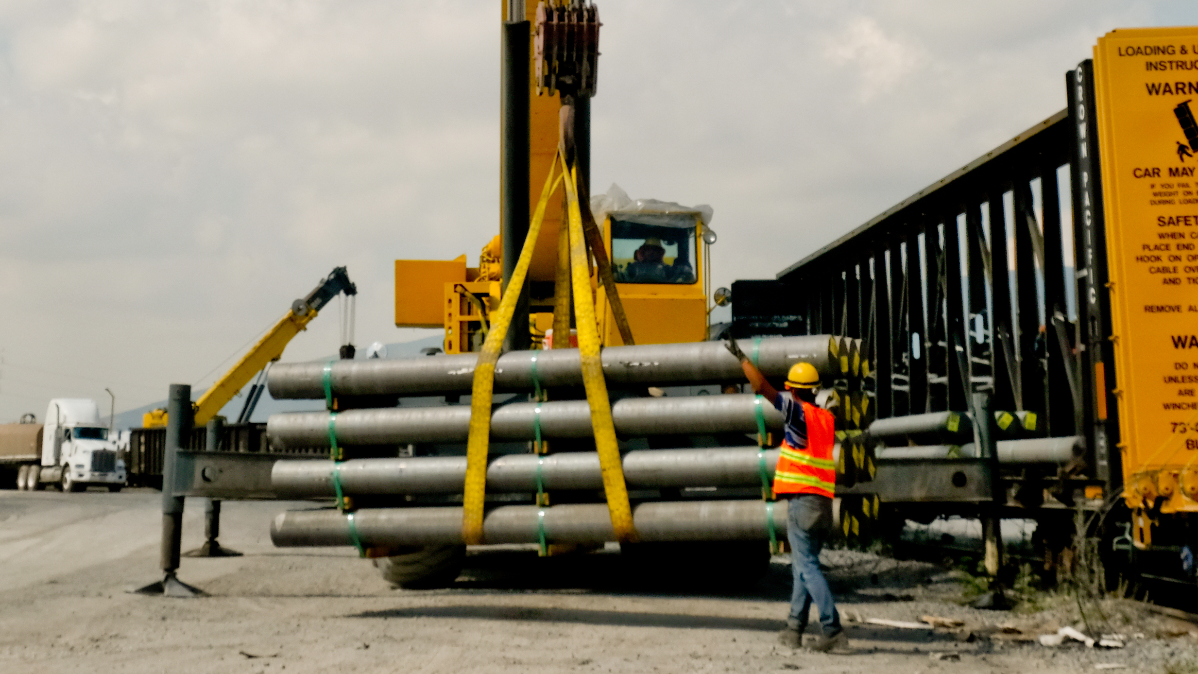 Terreno con vías ferroviarias, grúa hidráulica y camión para mover productos y materiales.